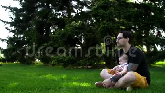 爸爸和女儿坐在草地上给她看远处的东西视频的预览图