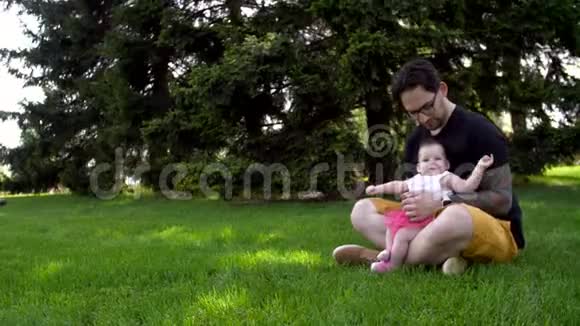爸爸和女儿坐在草地上给她看远处的东西视频的预览图