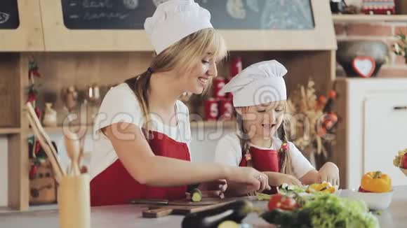 妈妈和小女儿在厨房做饭他们做一份新鲜的花园沙拉妈妈教女孩烹饪和烹饪视频的预览图