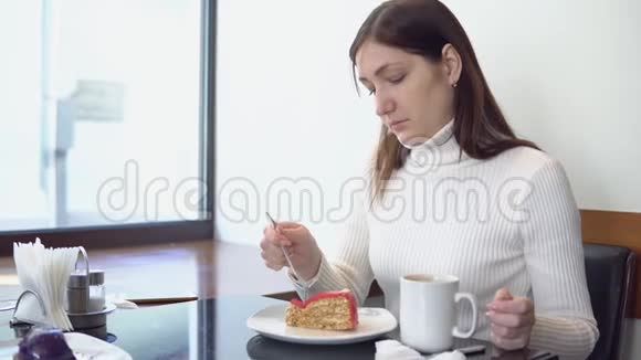 年轻女子喝咖啡在咖啡馆吃蛋糕视频的预览图