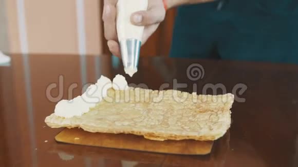 糕点厨师用男性的双手捏紧奶油夹在蛋糕层上视频的预览图