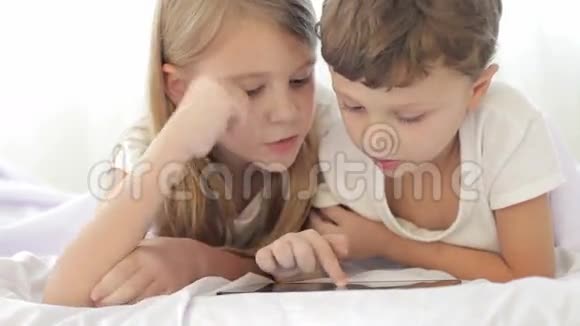 小女孩和男孩躺在房间的地板上用平板电脑视频的预览图
