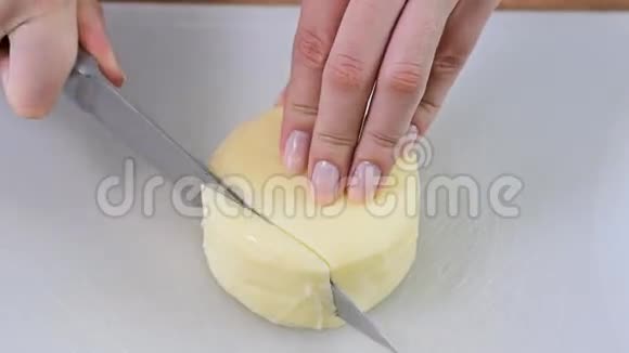 女性用手在木切割板上切割莫扎雷拉奶酪视频的预览图
