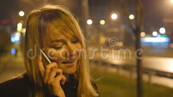 晚上在户外打电话的年轻女人有魅力的女孩在手机上说话的肖像关门视频的预览图