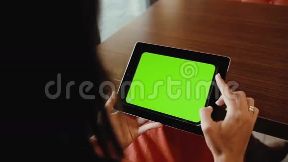 女人在桌子上用水平平板绿色屏幕视频的预览图