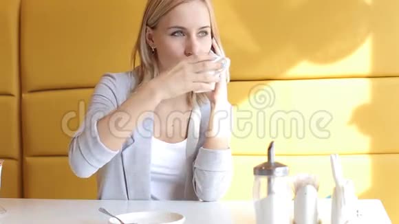 女孩搅拌喝茶在咖啡馆打电话视频的预览图