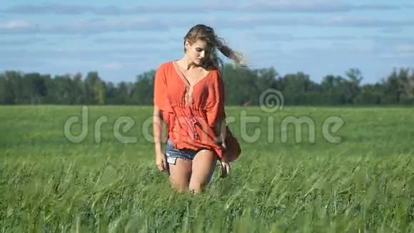 一个美丽的金发年轻浪漫女子穿着红色衬衫慢慢地走着看着她的整个画面视频的预览图