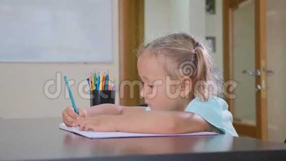 小可爱的女孩坐在教室里写作业本视频的预览图