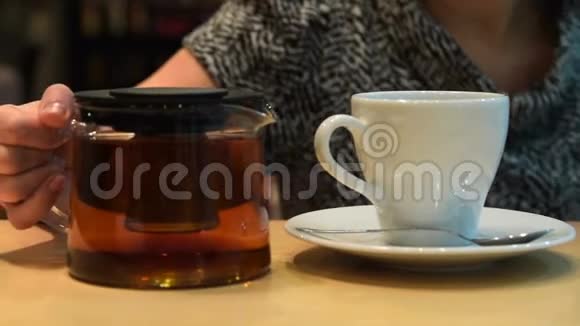 女人把茶倒进咖啡馆的杯子里视频的预览图