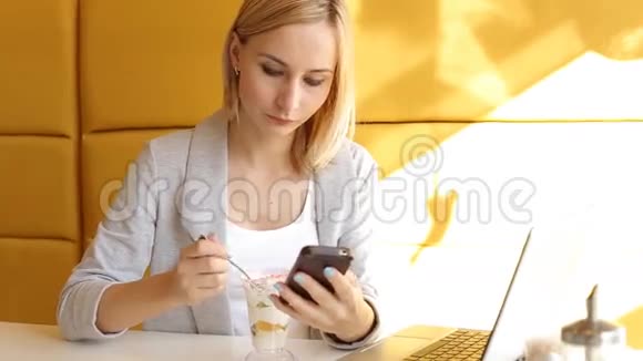 年轻女子在智能手机上发短信在咖啡馆吃甜点视频的预览图