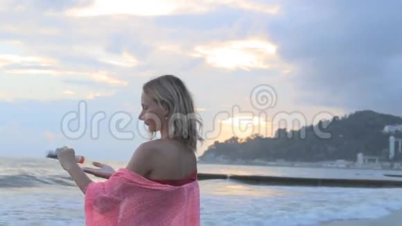 在波光粼粼的海面上一个温暖的女人在肩膀上涂防晒霜视频的预览图