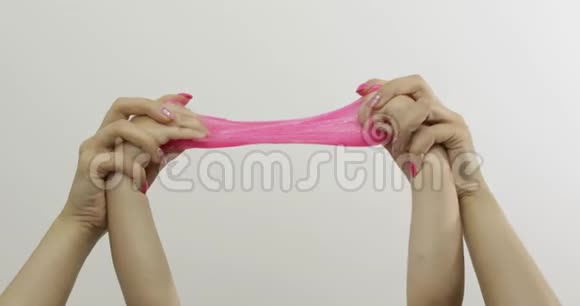 女人和孩子的手在白色背景上玩奇怪的粉红色黏液抗压力视频的预览图