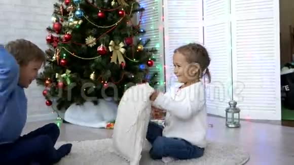 爱玩的兄弟姐妹在家中的圣诞树旁边打枕头视频的预览图