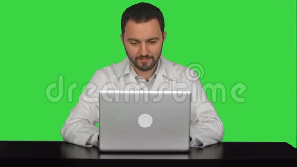 微笑男医生坐在桌上手提电脑视频的预览图