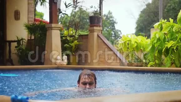 白人男子在游泳池慢游时会享受下雨的乐趣1920x1080视频的预览图