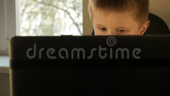 男孩的眼睛在电脑上工作时闭上视频的预览图