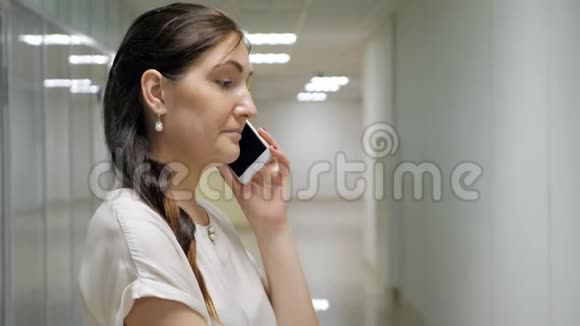 年轻女子在一栋办公楼的走廊上打电话视频的预览图