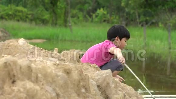 年轻的亚洲男孩在河边的泥坑里玩耍视频的预览图