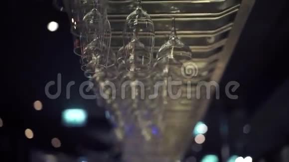 一组空酒杯挂在酒吧的金属横梁上视频的预览图