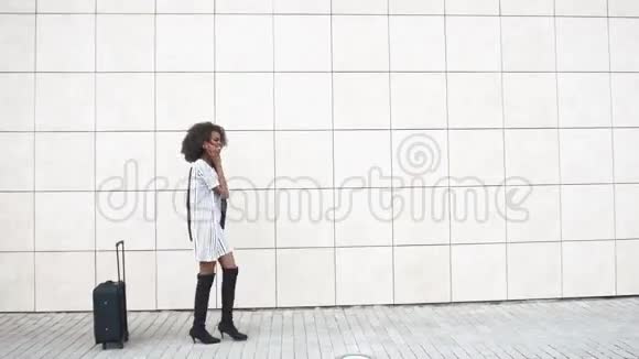 漂亮的非裔美国女商人在白色纹理的墙壁背景上通过电话交谈一个黑人女人视频的预览图