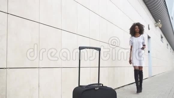 漂亮的非裔美国女商人带着她的行李去登机机场白墙视频的预览图