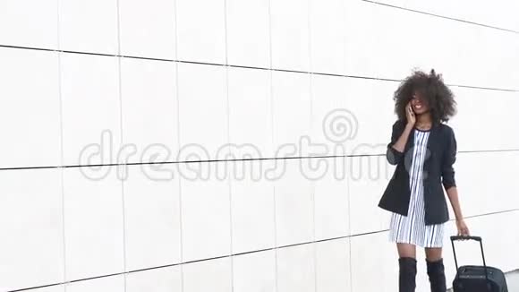 优雅的非洲裔美国妇女带着行李在机场白色纹理墙背景为航行做好准备视频的预览图