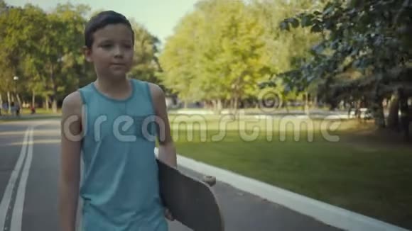 滑板手拿着滑板在公园里散步视频的预览图