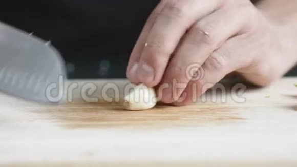 永满厨师用刀在切板上切薄片大蒜的正面视图视频的预览图