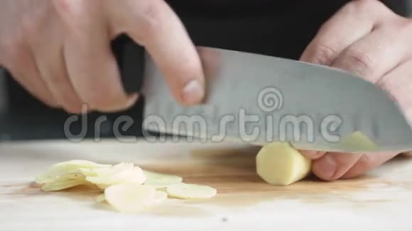 正面看年轻人厨师用刀在切板上切一片姜片视频的预览图