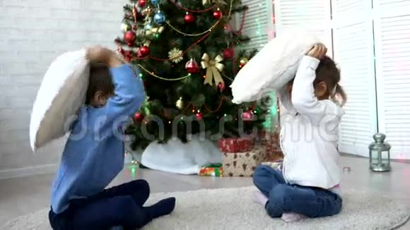 爱玩的兄弟姐妹在家中的圣诞树旁边打枕头视频的预览图