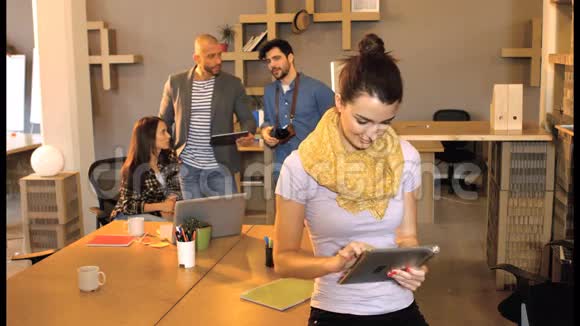 女性商务主管使用数码平板电脑而同事则在后台互动视频的预览图