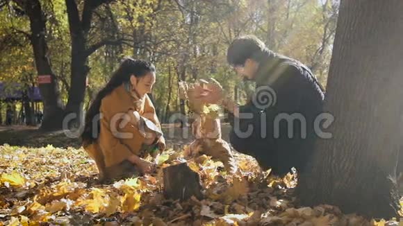 快乐的一家人在公园里玩秋叶妈妈和爸爸把柠檬扔到空中小孩子看着他们视频的预览图