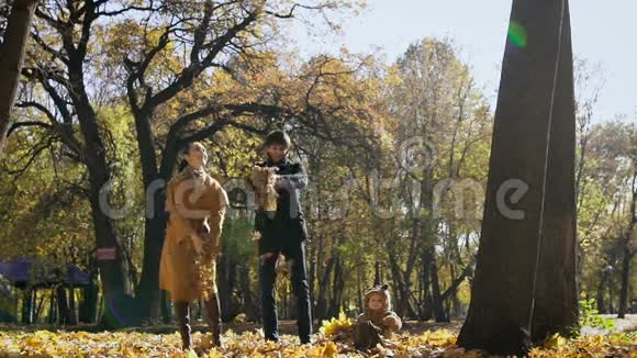 快乐的一家人在公园里玩秋叶妈妈和爸爸把柠檬扔到空中小孩子看着他们视频的预览图