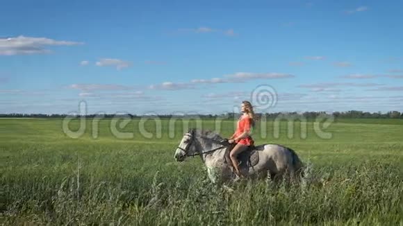 美丽的金发女郎穿着红色衬衫在乡下骑马视频的预览图
