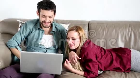 可爱的年轻人在家里用笔记本电脑看东西视频的预览图