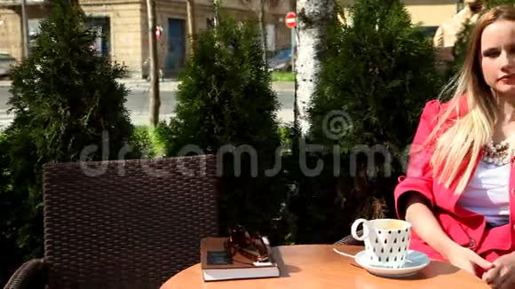 年轻的金发女人坐在咖啡店的椅子上视频的预览图