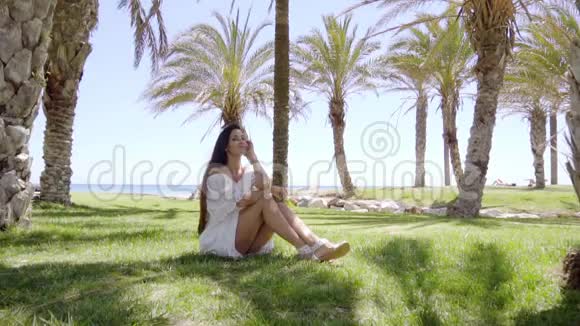 坐在棕榈树间的单身女人视频的预览图