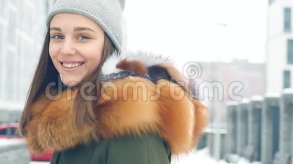 一位美丽动人的年轻女子微笑着穿过冬天的城市视频的预览图