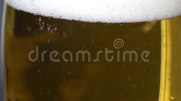 极端的特写啤酒泡沫在一个杯子里同时被倒入泡沫从啤酒杯的侧面滑下来喝一杯啤酒视频的预览图