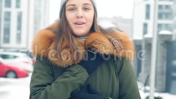 一位美丽动人的年轻女子微笑着穿过冬天的城市视频的预览图