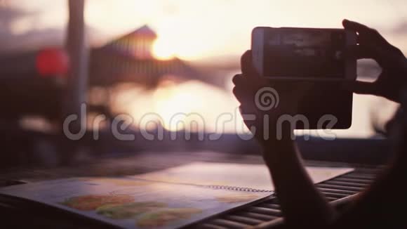 女人坐在咖啡馆海滩边用手机拍照把手举起来1920x1080视频的预览图