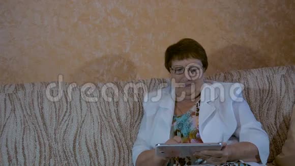 一位老年妇女正在看你的平板电脑照片视频的预览图