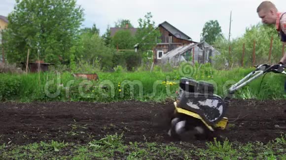 年轻的金发强壮的农民用旋转的迷你分蘖培育地面土壤视频的预览图