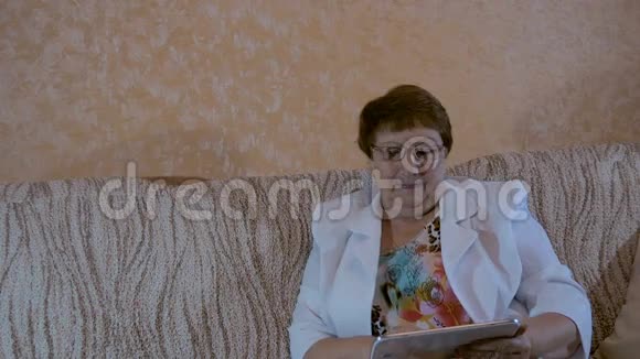 一位老年妇女正在看你的平板电脑照片视频的预览图
