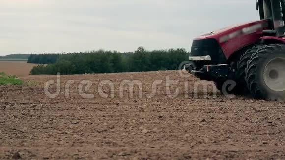 侧观一台农用拖拉机耕田一片泥土尘土飞扬特写视频的预览图