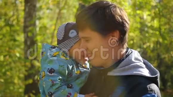 年轻的父亲在秋天公园的特写镜头中温柔地和婴儿玩耍视频的预览图