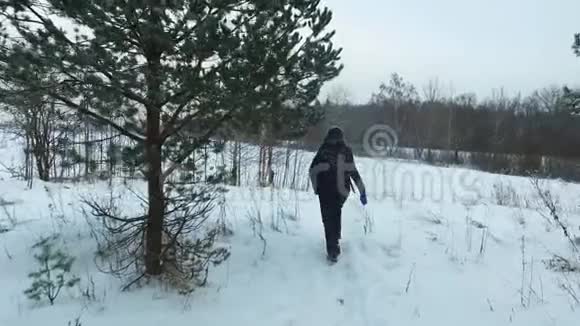 一位年轻女子在降雪时行走的慢速后视斯坦迪卡姆视频的预览图