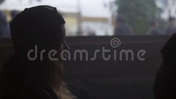 戴帽子的女孩坐在房间里她周围都是蒸汽在窗外看视频的预览图