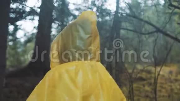 旅行者穿着黄色雨衣年轻的女徒步旅行者背着背包走过后景视频的预览图