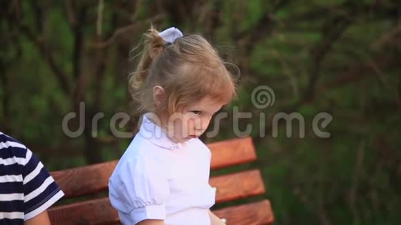 男孩吃冰淇淋坐在长凳上而女孩正在看视频的预览图